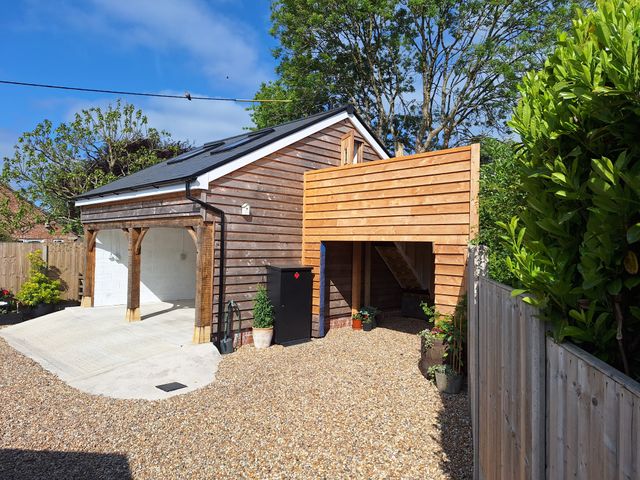 A wooden exterior garage with gravel driveway and plants in pots at The Halt in Maiden Newton