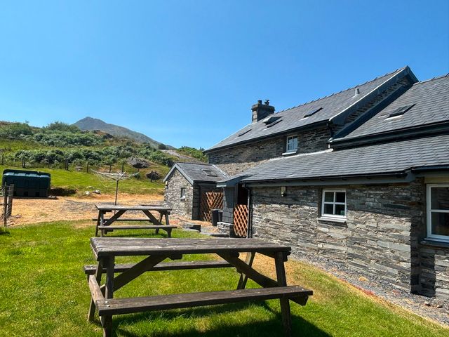 An outdoor area with benches and a cottage at Ty Siabod in Capel Curig near Betws-Y-Coed