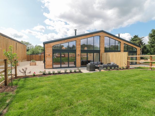 A modern house with large windows and patio seating at Murtry Barn in Frome