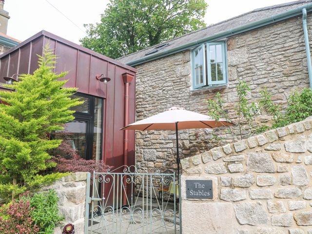 An outdoor area with a stone wall and an umbrella at The Stables in St Just