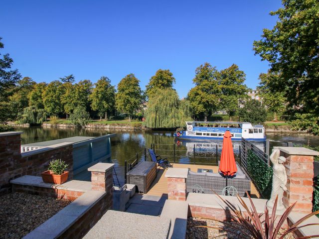 A garden with a river view and a boat at Riverside Cottage in Shrewsbury