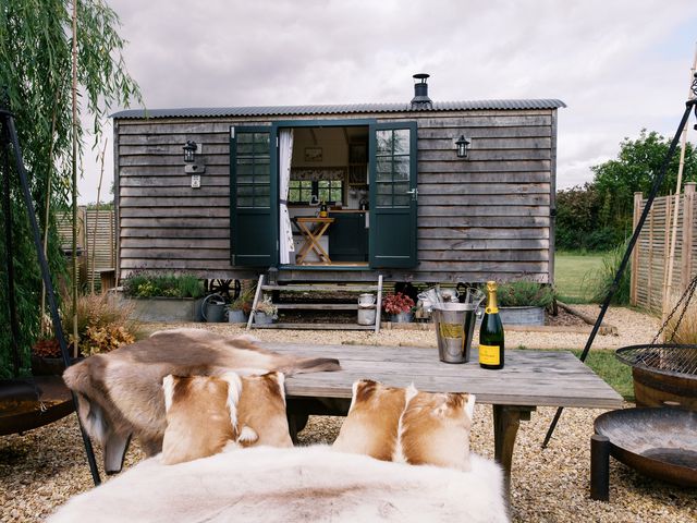 An outdoor space with a wooden cabin, table, and champagne at Poppie's Shepherds Hut at Shepherds Lodge Retreat and Wellness Bottesford near Redmile and Vale of Belvoir