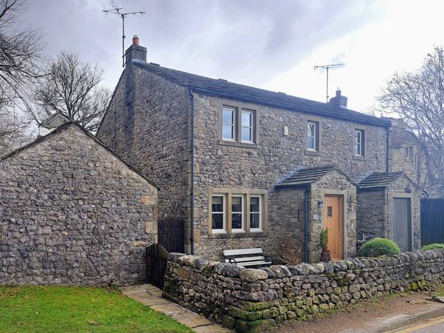 A stone house with a door and windows at Woodside Cottage in Malham