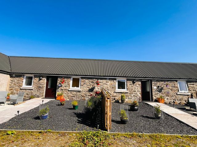 An outdoor area with a stone building and planters at Bathach Mor Balvicar, Isle Of Seil
