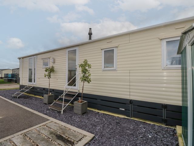 The exterior of a beige mobile home with two steps leading to two doors and potted plants outside at Dunlin Walk 13 Hayling Island