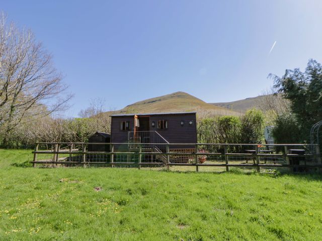 An outdoor area with a hut and fenced grassland at Bill’s Shepherds Hut near Talgarth