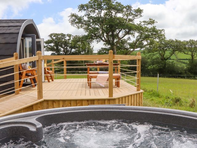 An outdoor deck with a hot tub, table, and chairs at Under Oak Pod in Totnes