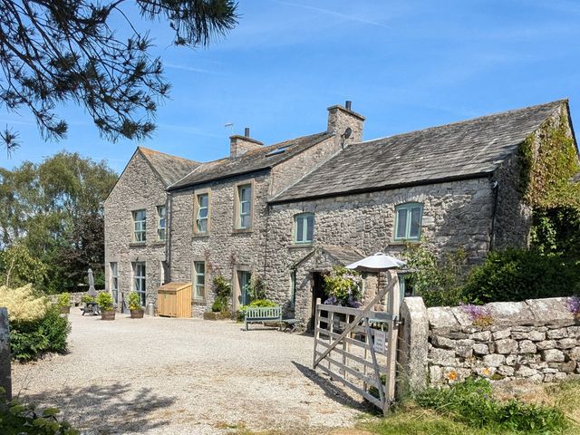 A stone house with a garden and parking area at The Little Farmhouse in Carnforth