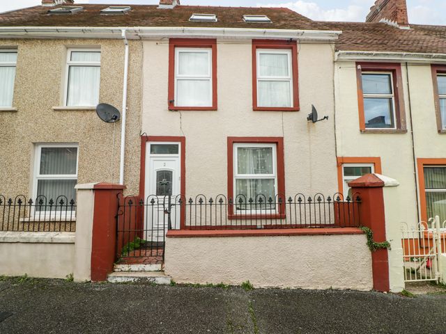 A terraced house with two upper windows and one lower window a white door and a black iron fence at 3 Vicary Street in Milford Haven