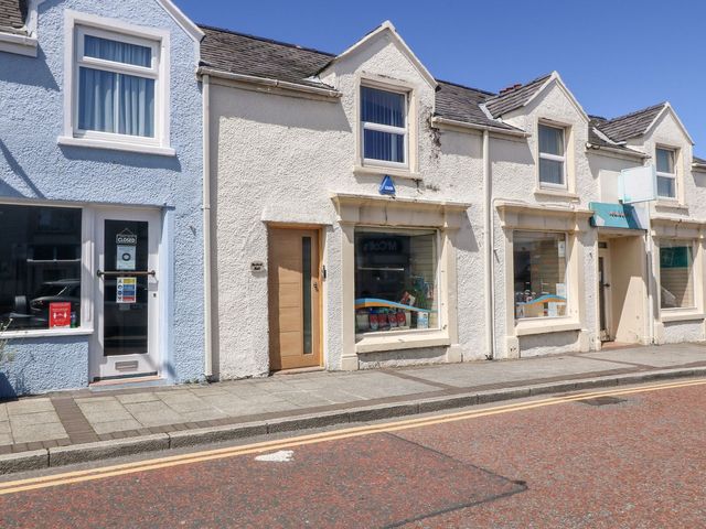 A street view of small commercial buildings with display windows and doors at Medical Hall in Cemaes Bay