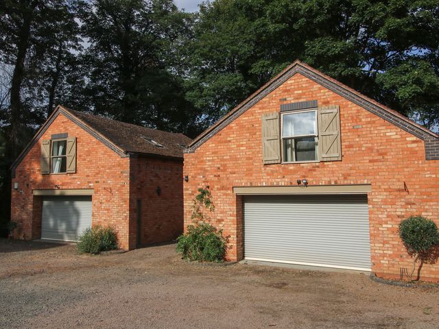 Two brick houses with garages and windows at Old Forge Apartment in Cookley