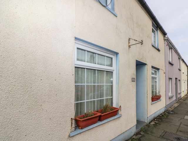 A row of houses with white framed windows and flower boxes on a paved sidewalk at 25 St James Street in Narberth