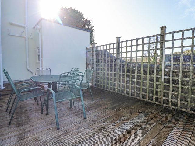 An outdoor wooden deck with a metal table and six metal chairs and a wooden trellis at The Fir Grove Annex in Menai Bridge