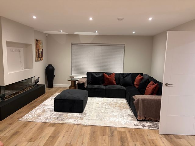 A living room with a sectional sofa and a fireplace at Cross Winds in Clapham