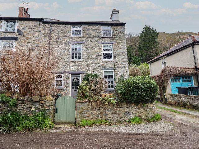 A stone cottage with a door and windows at Riverwash Cottage Dwygyfylchi