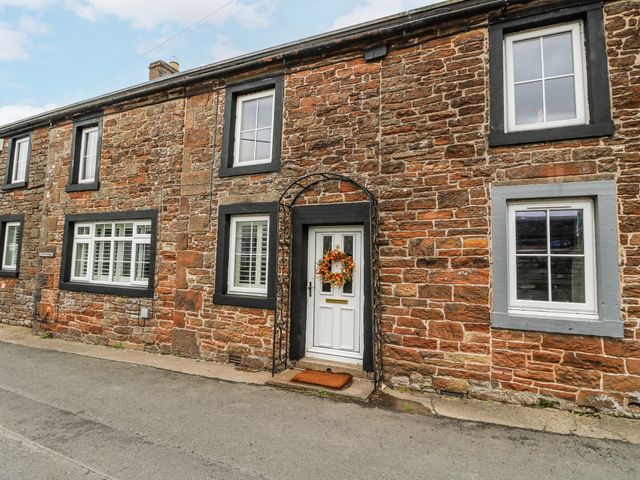 A stone house with a front door and windows at Daisy Cottage in Wigton