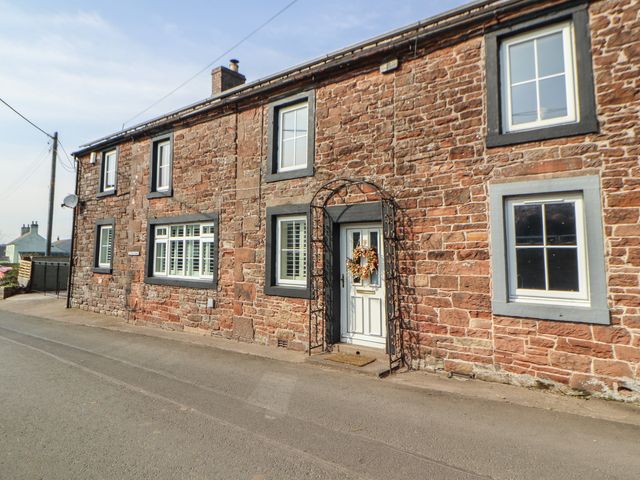 An exterior view of a stone house with a door and windows at Daisy Cottage near Wigton