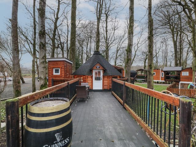 A wooden hut with a conical roof at the end of a wooden walkway with railings surrounded by trees at Hexagon Hut - Dec Update in Dungiven Londonderry