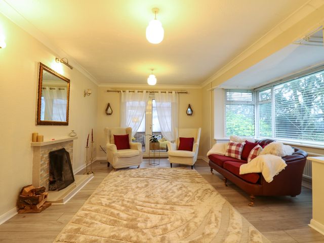 A living room with two armchairs a sofa a fireplace and large windows at Crown Farm Near Upwell