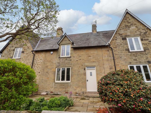 A house with a door and windows surrounded by bushes at 9 Longhirst Village in Morpeth