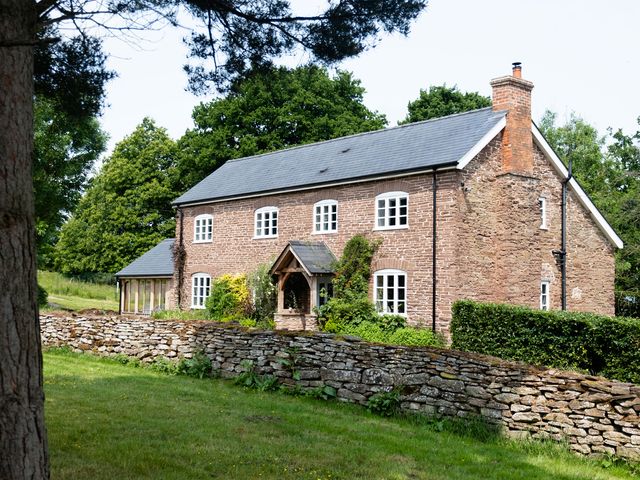 A house with a stone wall and trees at Henhouse Farm in Bodenham