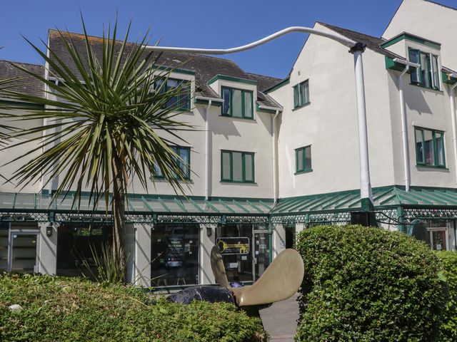A building with green window frames and a glass awning with a palm tree and a large metal sculpture in front at Eve's Attic in Bowness-On-Windermere