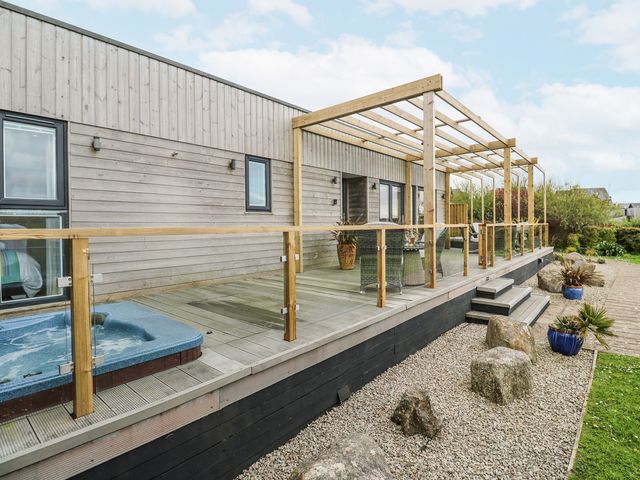 An outdoor area with a hot tub and wooden deck at Petroc in Portreath