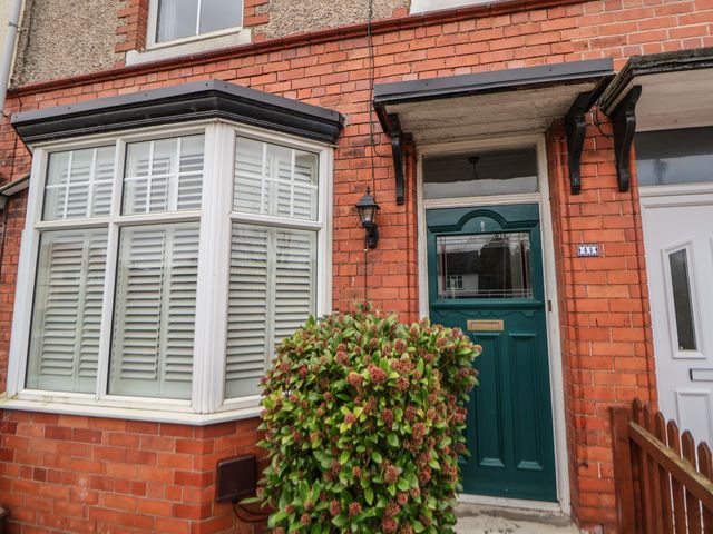Front entrance with a green door, bay window with white shutters, and a shrub in front of a brick house at 45 Brook Lane in Chester