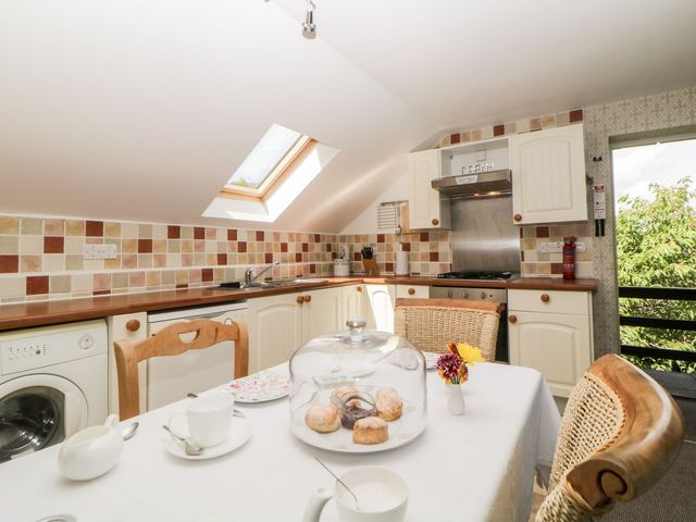 A kitchen with a dining table set for tea and a skylight above at The Hayloft in Lostwithiel
