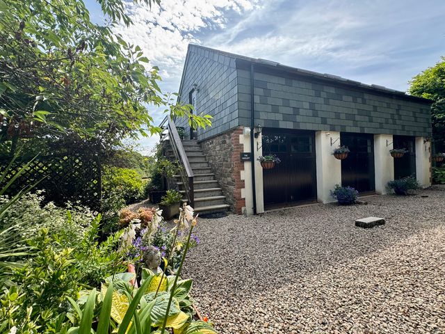 A garden view with steps leading to a building at The Hayloft in Lostwithiel