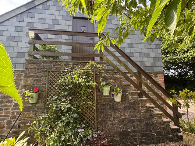 An outdoor staircase leading to a door with plants at The Hayloft in Lostwithiel