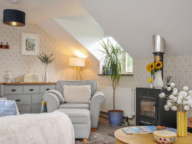 A living room with a chair and table at The Hayloft in Lostwithiel
