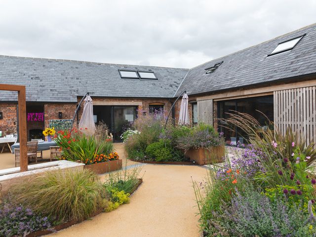 An outdoor courtyard with plants and flowers in raised beds and patio furniture at The Stables in Galteemore Farm in Avebury near Marlborough