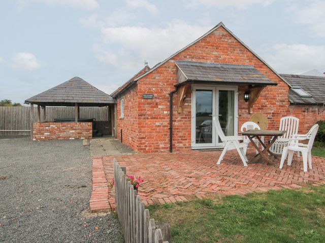 An outdoor area with a brick cottage and seating at Millstone Cottages - Millstone Cottage in Westbury