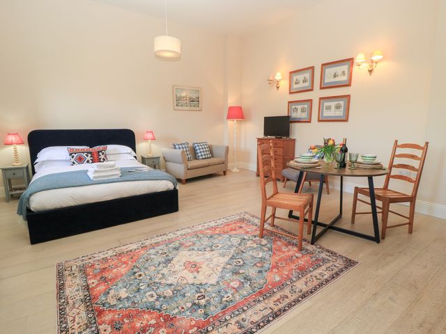 A bedroom with bed sofa dining table and chairs with a rug on the floor at Swallow Studio in Andoversford near Cheltenham
