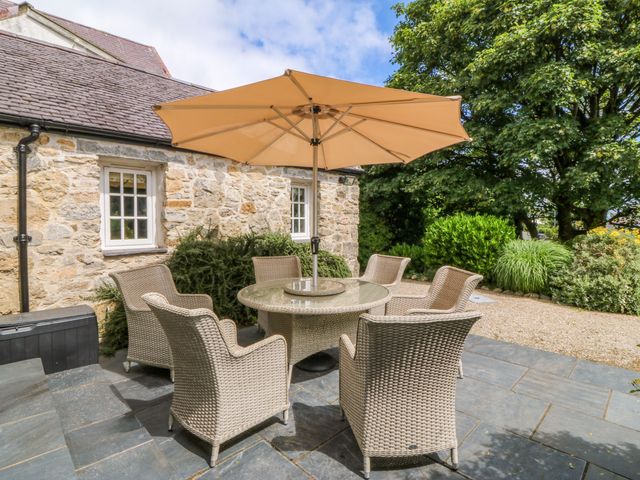 A patio area with a table and chairs at Tyddyn Iolyn in Benllech
