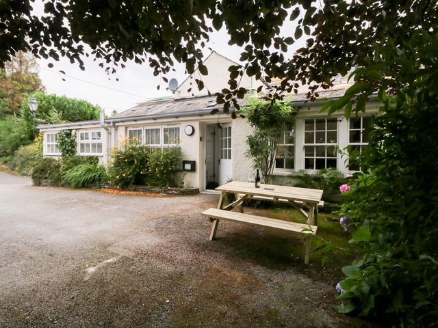 A house exterior with a bench and bushes at Pippins in Ambleside