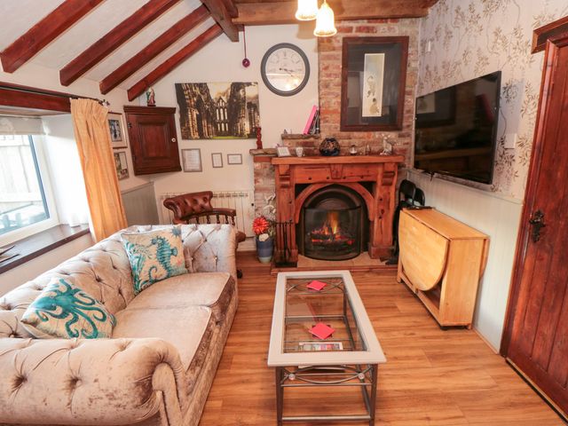 A living room with a sofa coffee table fireplace and a wall mounted television at The Old Mill Cottage Low Hawsker near Whitby