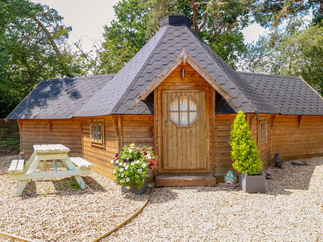 A cottage with a wooden door and picnic table at Enchanted Cottage in Snettisham