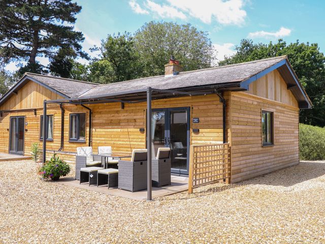 A cabin with patio furniture outside at Rabbit Warren Lodge in Snettisham