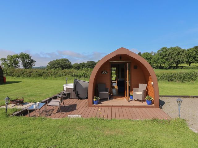 A glamping pod with a wooden deck and outdoor seating at Ty Twt Teifi in Tregaron