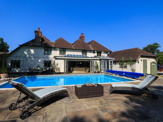 A swimming pool with lounge chairs and table at Beam Cottage in Warsash