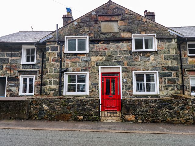Stone house with a red front door and white framed windows at Si-Yr-Afon in Beddgelert