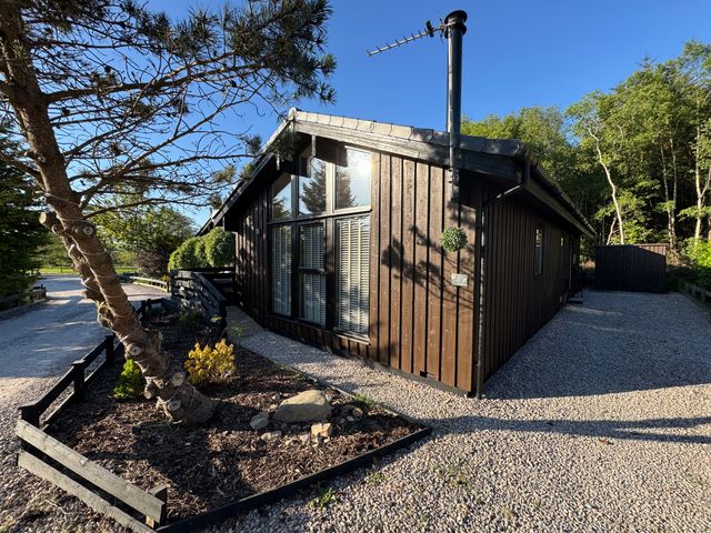 A cabin with a chimney and gravel path at Fig Tree Lodge in Hutton Roof near Penrith