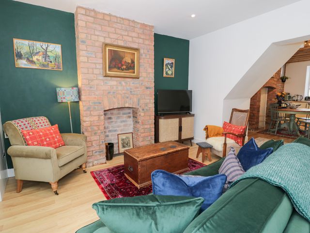 A living room with a green wall and brown furniture at Derwen House in Llangollen