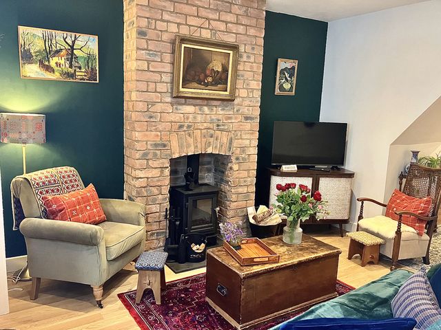 A living room with a fireplace and seating arrangements at Derwen House in Llangollen