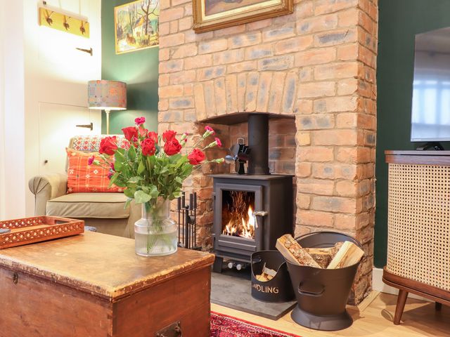 A living room with a fireplace and flowers on a table at Derwen House Llangollen