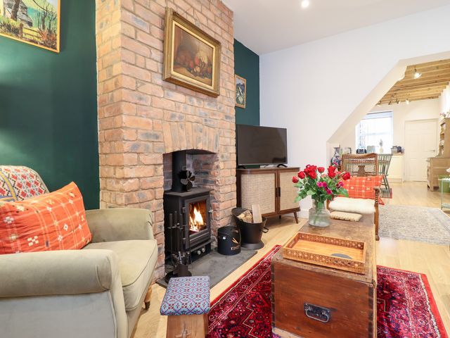A living room with a wood stove and a coffee table at Derwen House in Llangollen