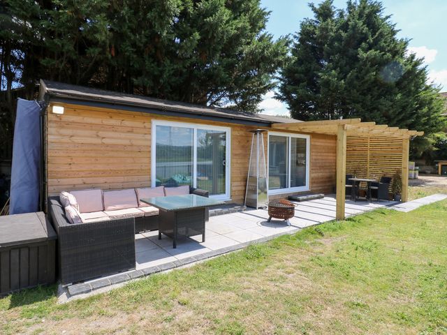 An outdoor seating area with a glass table and a wooden cabin at Haymens Wharf Wouldham