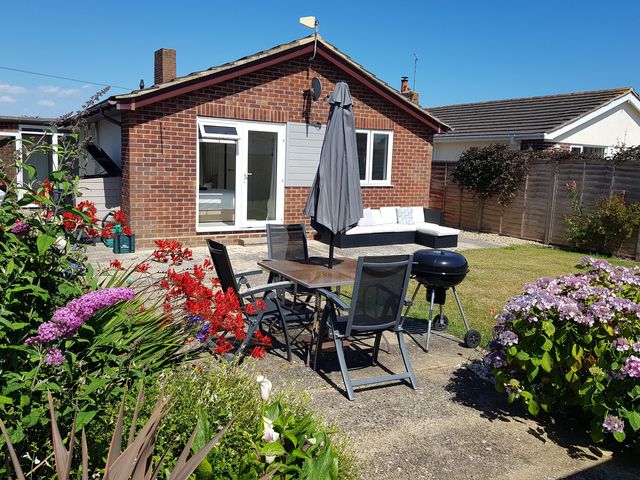 A garden area with table and chairs plus a barbecue at Seafarer's Rest in Selsey